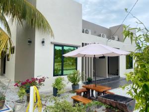 a patio with a wooden table and an umbrella at NitaDinn Guest House in Kampong Ru Sepuloh
