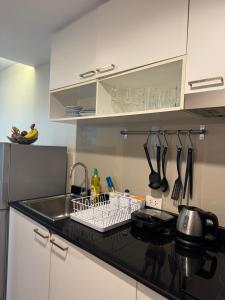 Una cocina con fregadero y escurridor de platos con utensilios. en Pool Access Beachfront Studio, en Phuket