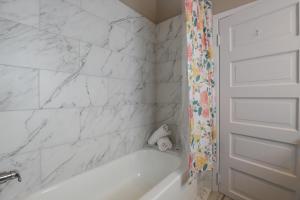 a white bathroom with a tub and a shower curtain at 4BR The Montrose Caliber, Grandeur Home, Near All in Houston