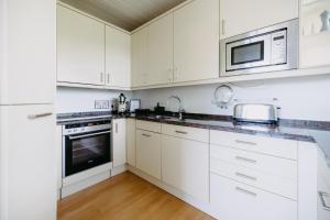 a white kitchen with white cabinets and a microwave at Burgenland Hideaway in Bad Tatzmannsdorf