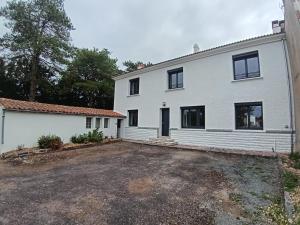 ein weißes Haus mit einem Parkplatz davor in der Unterkunft 285 - gite de la rue du Chateau Aizenay in Aizenay