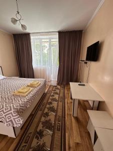 a bedroom with a bed and a desk and a television at Boomerang Guest house in Cholpon-Ata