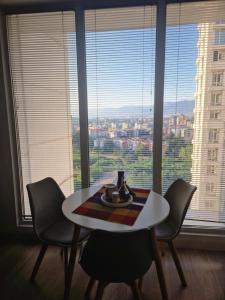 a table and chairs in a room with a large window at Bloom Apartments B in Skopje