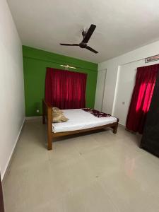 a bedroom with a bed with a red curtain at Sreenidhi Apartment Guruvayoor in Guruvāyūr