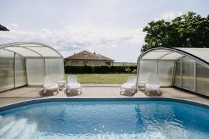 a pool with two gazebos and chairs next to it at Burgenland Hideaway in Bad Tatzmannsdorf