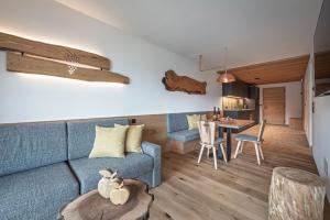 a living room with a blue couch and a table at Knöspele - Brennerei & Genuss-Apartments in Brixen