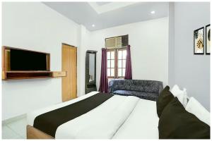 Un dormitorio con una cama, un televisor y una silla. en Hotel Imperial Residency, en Puri
