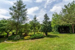 a garden with trees and grass and a building at Lake Experience - Casa de vacanta in Măineasca +9 photos