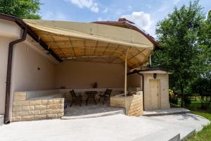 a patio with a table and chairs under awning at Lake Experience - Casa de vacanta in Măineasca
