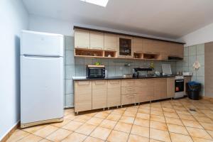 a kitchen with wooden cabinets and a white refrigerator at Lake Experience - Casa de vacanta in Măineasca