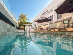 a swimming pool with chairs and umbrellas next to a building at Villa Poseidon Grupo AC Gestion in Zahara de los Atunes