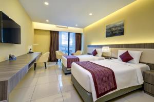 a hotel room with two beds and a desk at Highland Breeze Hotel in Genting Highlands