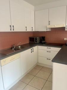 a white kitchen with a sink and a microwave at Beachside Family Apartment Windstar 402 in Oostduinkerke