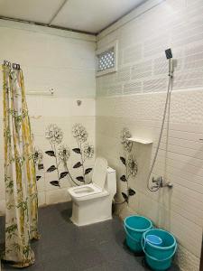 a bathroom with a toilet and flowers on the wall at LAKSHMI NIKUNj Estate Stay in Madikeri