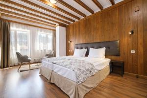 拉兹洛格Hotel Razlog的一间卧室设有一张带木墙的大床