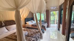 a bedroom with two beds and a canopy bed at Rumah Irak et Kadek Bali in Ubud