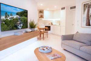a living room with a couch and a tv on a wall at Netanya Noosa Beachfront Resort in Noosa Heads