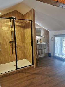 a glass shower in a room with a wooden floor at Domaine de Pourrouquet - Demeure de charme et Gîte in Vic-Fezensac