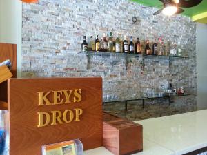 a bar with a keys drop sign on a brick wall at Purimas Resortel in Rawai Beach