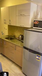 Una cocina con frigorífico de acero inoxidable y fregadero. en قرية أكوا فيو الساحل الشمالي - Aqua View El Alamein, en El Qasaba esh Sharqīya