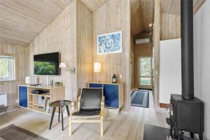 a living room with wood paneling and a stove at 1431-Aakirkeby-Strandvangen-13-B in Vester Sømarken