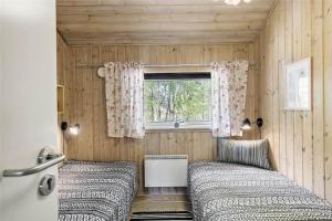 two beds in a small room with a window at 1431-Aakirkeby-Strandvangen-13-B in Vester Sømarken