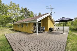a yellow house with a deck and an umbrella at 1431-Aakirkeby-Strandvangen-13-B in Vester Sømarken