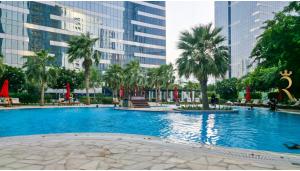 Una gran piscina con palmeras y edificios. en Gate view Glow 1BR in Al Reem Island, en Abu Dabi