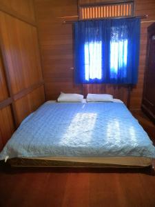 a bed in a room with a blue window at Pairi's Family Homestay in Rantepao