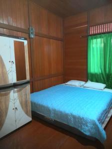 a bedroom with a blue bed with a green curtain at Pairi's Family Homestay in Rantepao
