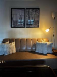 a brown leather couch in a living room with three pictures at 3 BR Luxe Penthouse nearby Harkipauri by Manstays in Haridwār