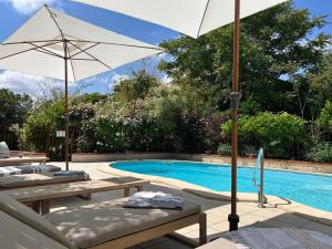 a pool with chairs and umbrellas next to a pool at Le Mas de la Prade in Bages