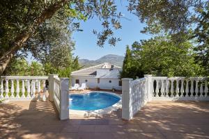 a white fence around a swimming pool with a house at Casa Rural La Atalaya in Castillo de Locubín