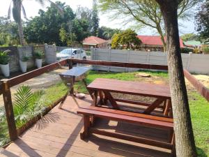 Una mesa de picnic y un banco junto a un árbol. en Puravida guesthouse, en Umkomaas 6 fotos más