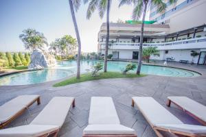 a swimming pool with chaise lounge chairs in front of a building at Topland Hotel & Convention Centre in Phitsanulok