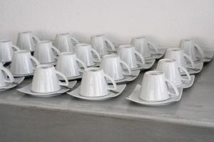 a row of white cups and saucers on a table at Lagada Beach Hotel in Adamantas
