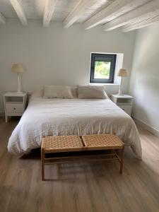 a white bedroom with a large bed and a table at El Molino del Burgo de Osma in El Burgo de Osma