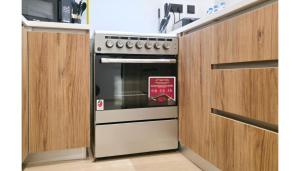 a oven in a kitchen with wooden cabinets at Comfort Cove 1BR- 2 Minutes Walk to Al Maryah Fireworks in Abu Dhabi
