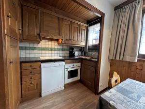 a small kitchen with wooden cabinets and white appliances at Resse - Appartement 3 pieces centre in La Clusaz +4 photos
