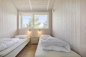 Dos camas en una habitación pequeña con ventana. en 1448-Aakirkeby-Havrebakken-18, en Vester Sømarken
