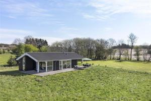 una pequeña casa negra en un campo de hierba en 1448-Aakirkeby-Havrebakken-18, en Vester Sømarken