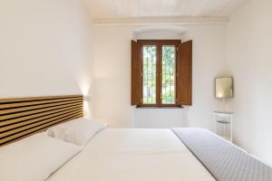 a white bedroom with a bed and a window at Casa Sulis Holiday Home in Tortolì