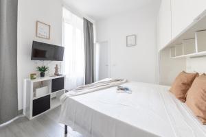 a white bedroom with a bed and a tv at Magic Rent - Appartamento Gluck in Milan