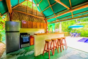 a kitchen with a bar with stools in it at Aloha Surf Nosara - Kahala Hui Cabins #3 in Nosara