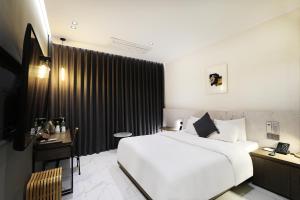 a bedroom with a large white bed and a desk at Pangyo KYND Tourist Hotel - Foreign Tourist Tax Return Hotel in Seongnam