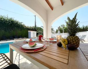 a wooden table with fruit and wine glasses on a patio at Villa Besuc Benissa Moraira 8 personnes in Benissa