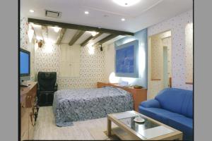 a hotel room with a bed and a blue couch at ホテルパークアベニュー in Nagoya