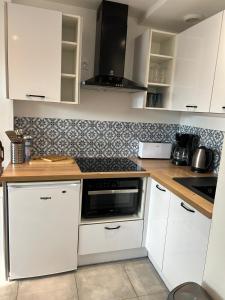 a kitchen with white cabinets and a counter top at Le Lotus Oasis des Pins avec piscine in Labenne +2 photos