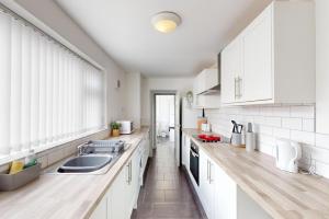 a kitchen with white cabinets and a sink at Sunderland Cosy Cottage in Sunderland