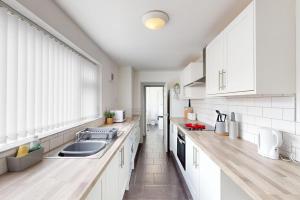 a kitchen with white cabinets and a sink at Sunderland Cosy Cottage in Sunderland
